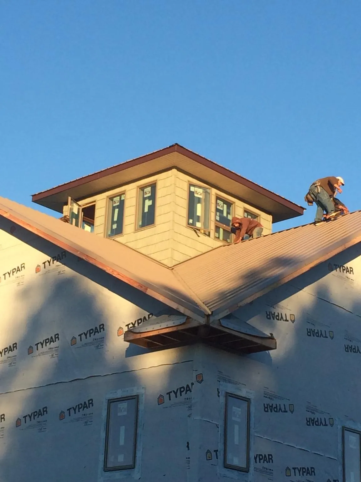 Roofers working around a rooftop cupola on a new metal roof at sunset — Roof Waterproofing in De Soto by Roofing Brothers